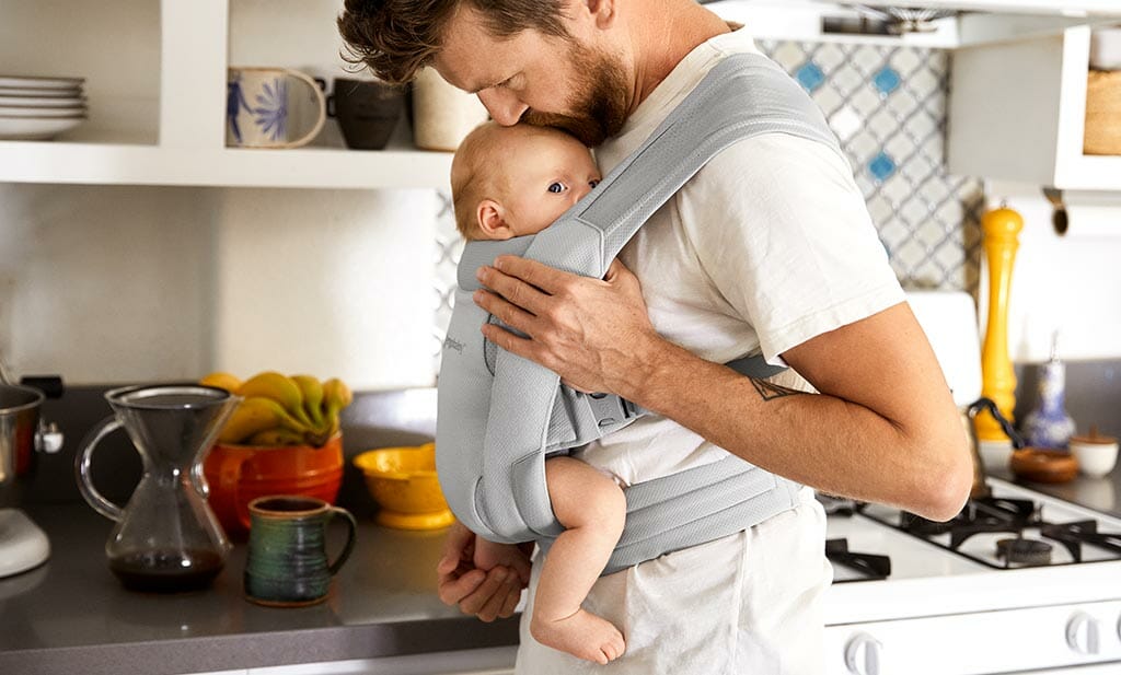 Dad carries a baby in Ergobaby Embrace 